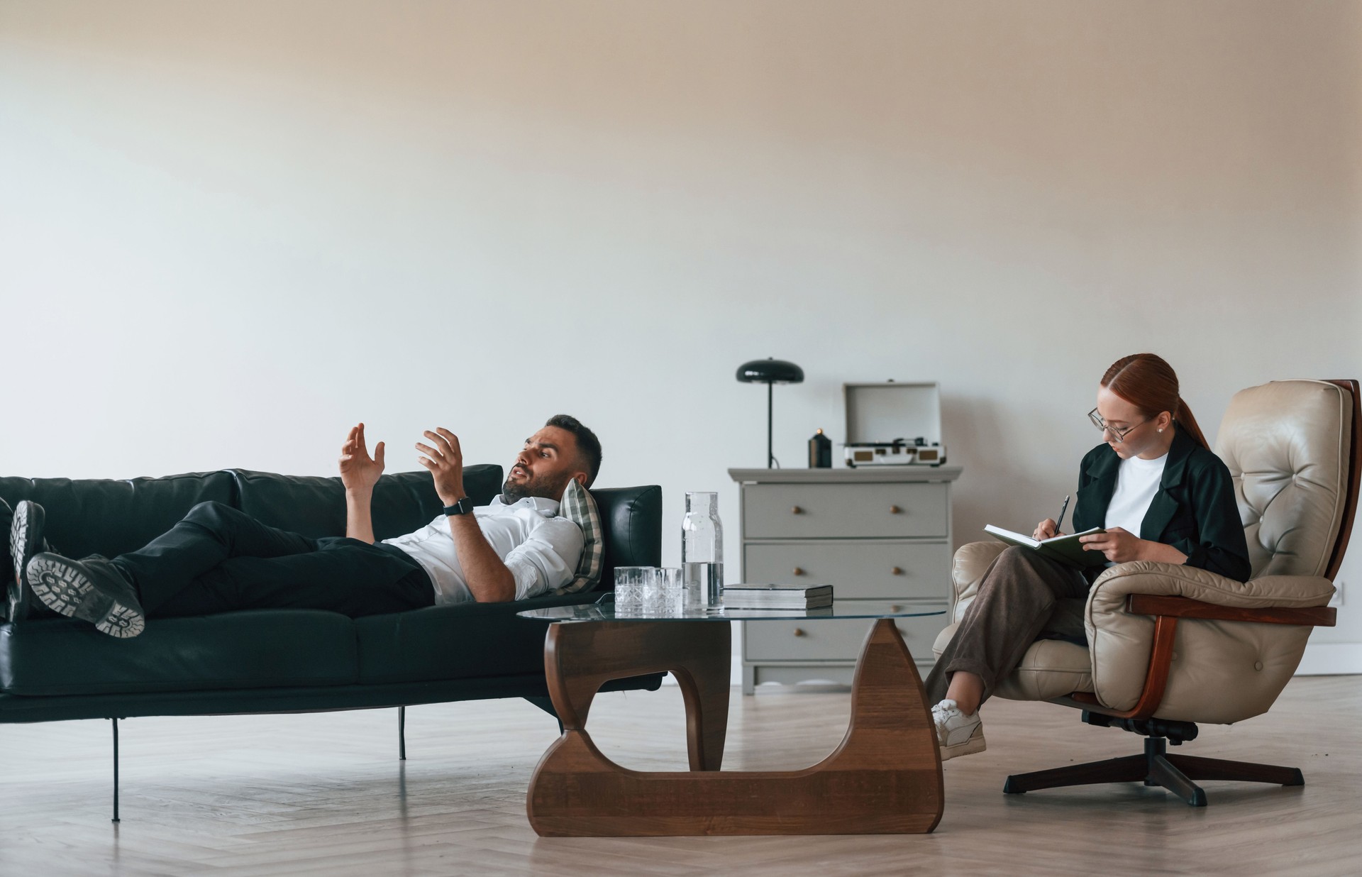 Man is lying down on the sofa, session with woman psychologist