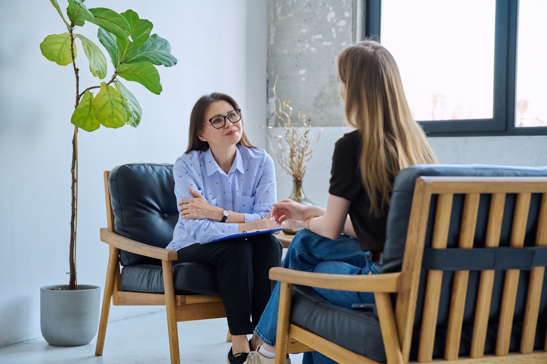 Female professional mental specialist, therapist working with patient young woman in office
